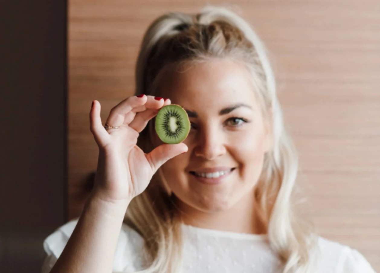 woman with kiwi in front of eye immune-boosting foods concept
